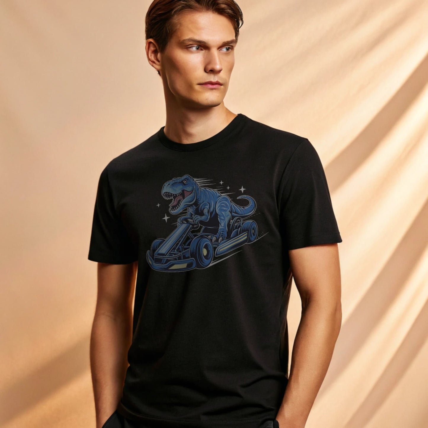 Male model wearing a black crew-neck t-shirt with a blue dinosaur kart graphic, studio shot on a warm-beige background.