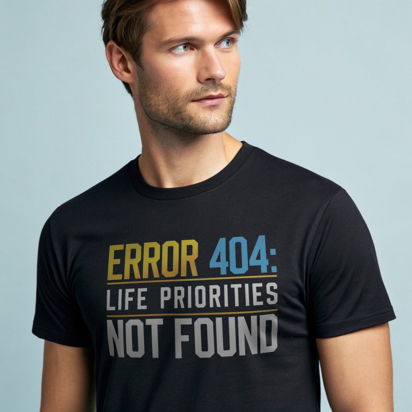 Male model wearing a black crew-neck t-shirt with “Priorities Not Found” tech graphic, studio shot on a smooth pale-blue background.
