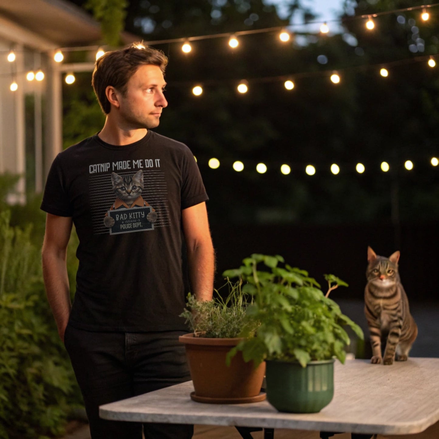 Black lifestyle mockup of Catnip Made Me Do It T-Shirt on a male model by a patio at dusk, plain crew neck