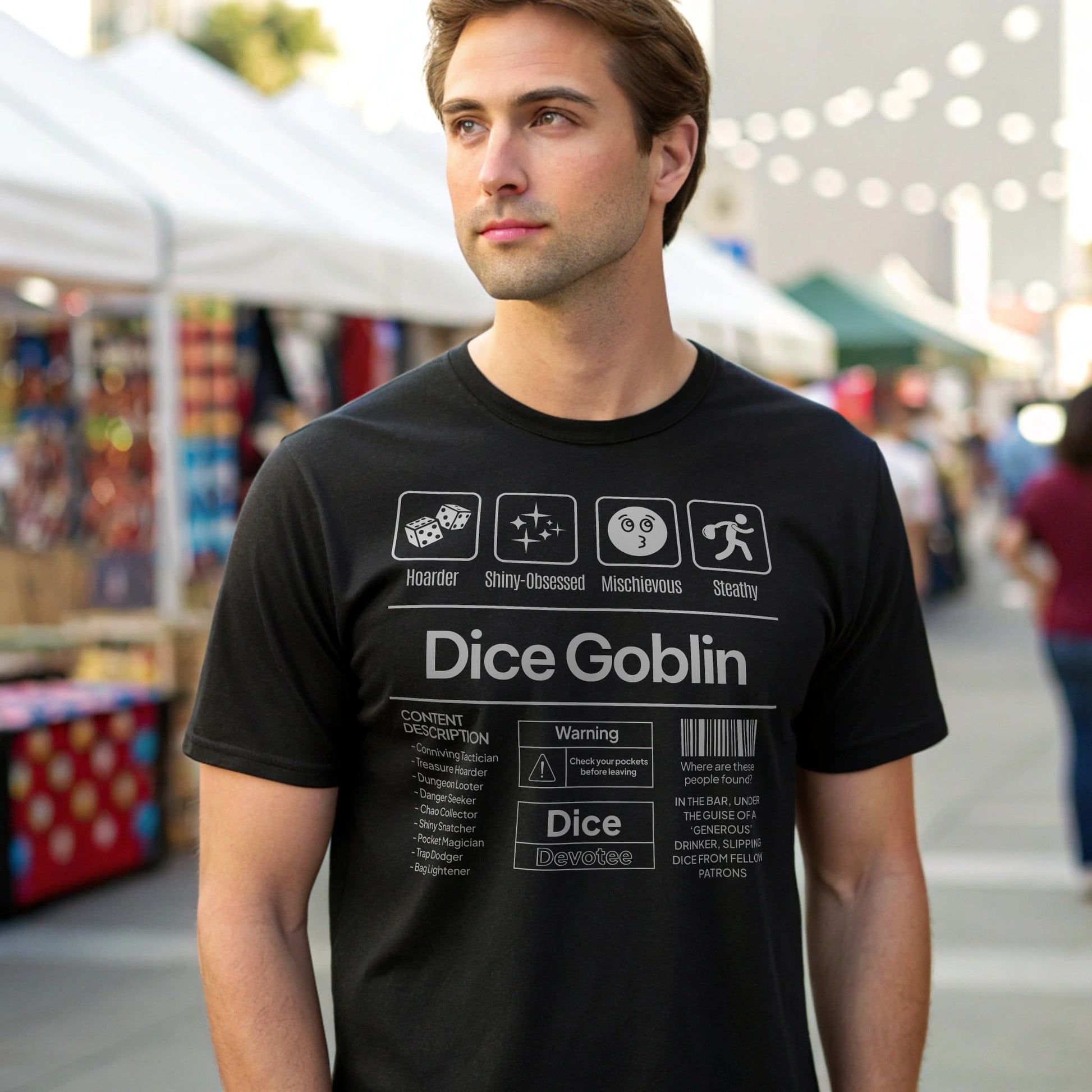 Black lifestyle mockup of Dice Goblin T-Shirt on a male model at an outdoor market convention with white vendor tents and string-light bokeh in the background, plain crew neck.
