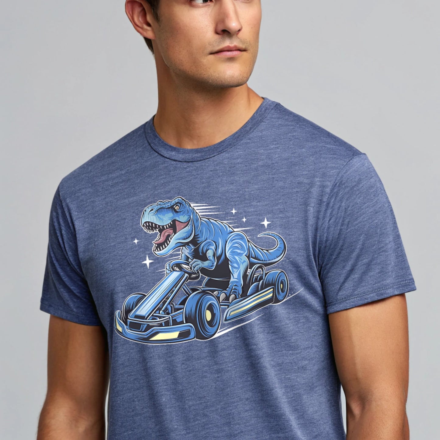 Male model wearing a heather indigo crew-neck t-shirt with a blue dinosaur kart graphic, studio shot on a smooth pale-gray background.