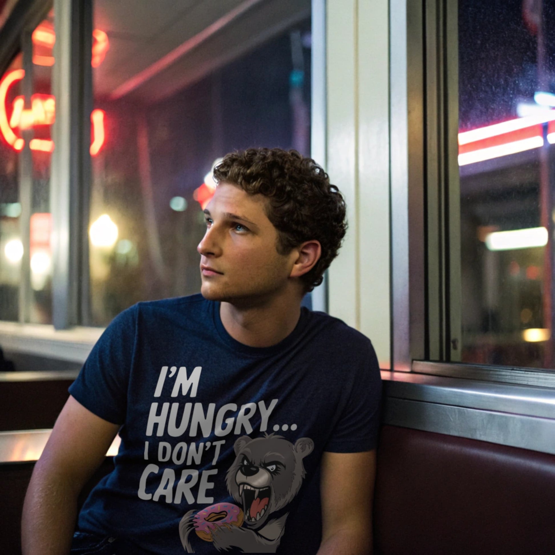 Man wearing navy “I’m Hungry… I Don’t Care” t-shirt sitting in a retro diner booth