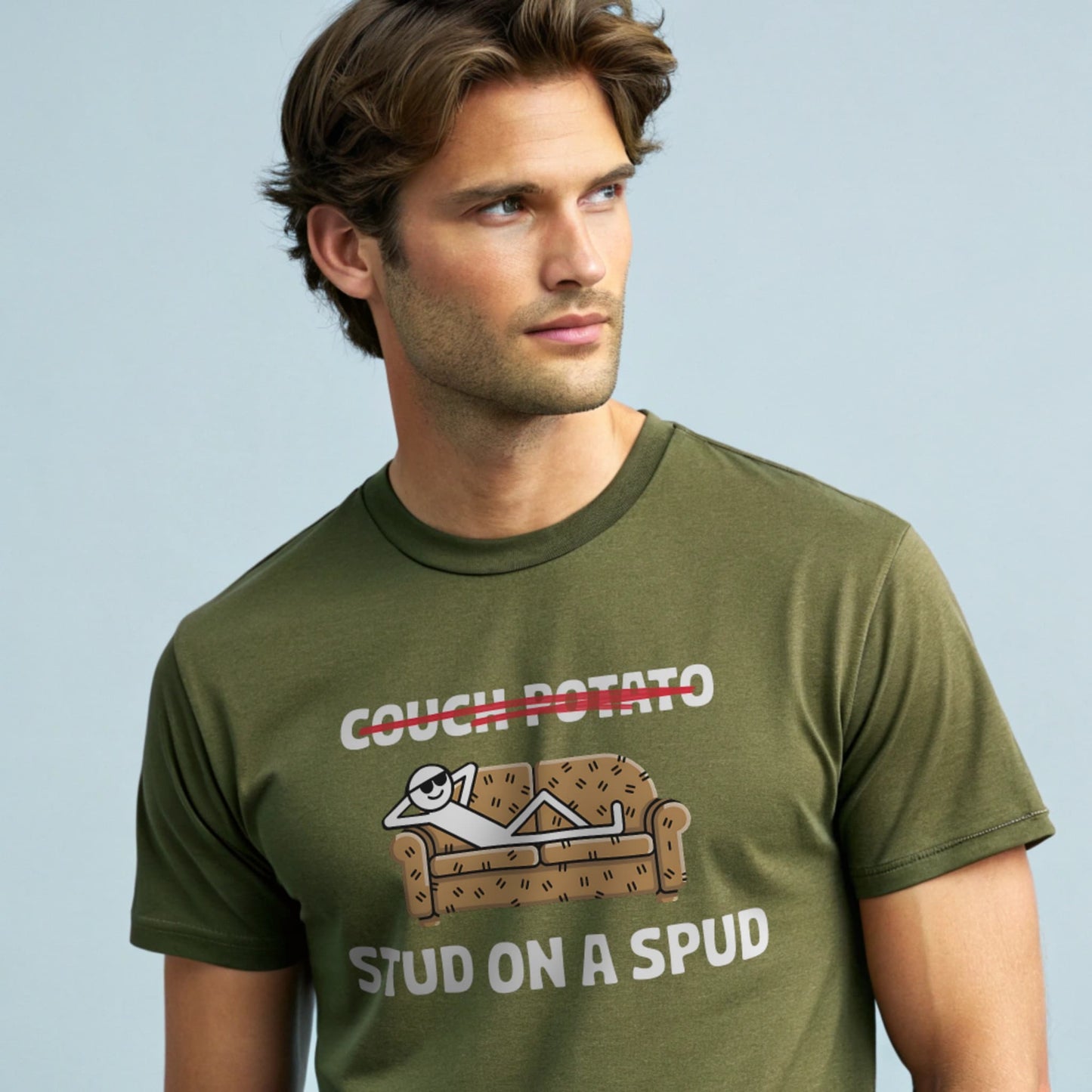 Male model wearing a military green crew-neck t-shirt with “Couch Potato: Stud on a Spud” graphic, studio shot on pale blue background.