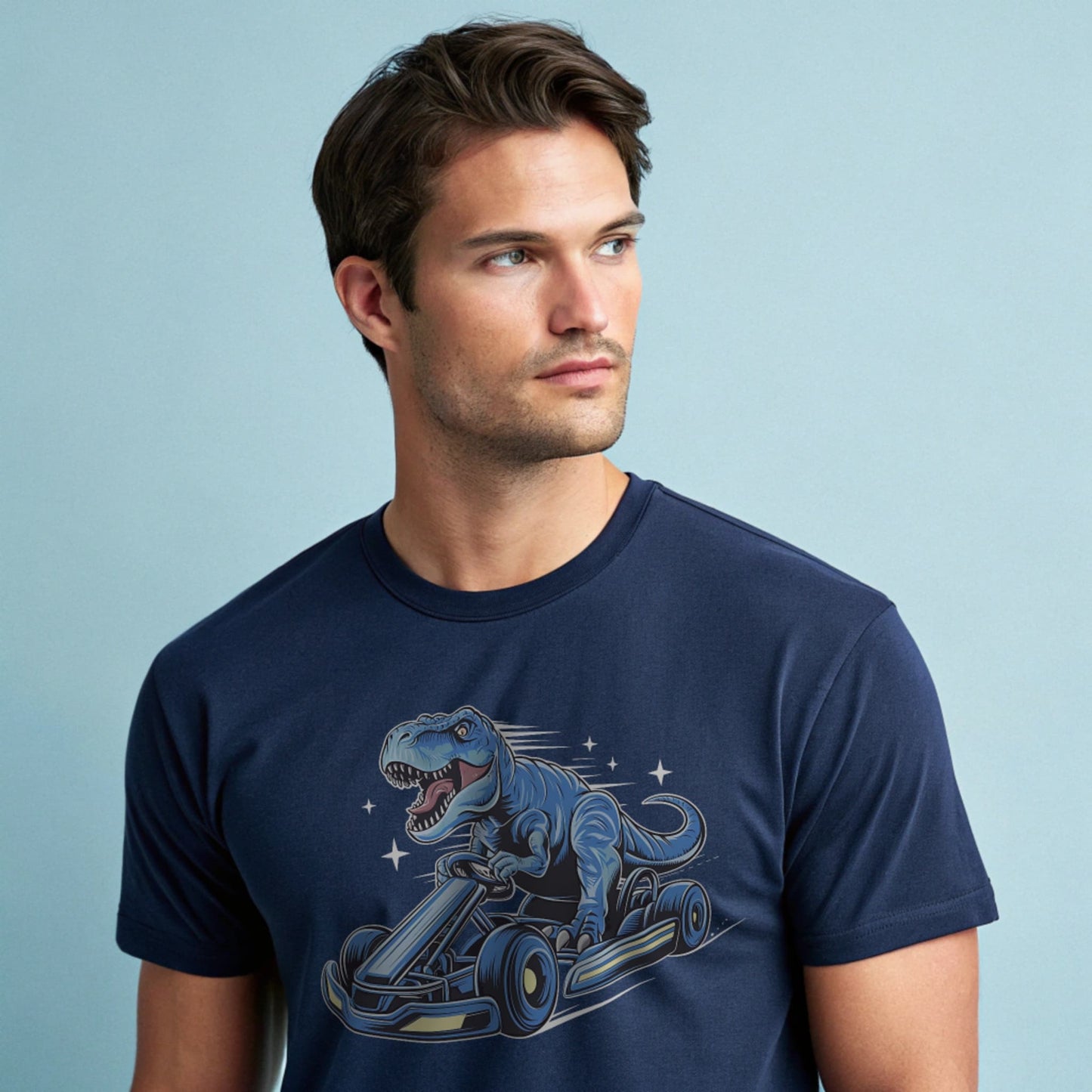 Male model wearing a navy crew-neck t-shirt with a blue dinosaur kart graphic, studio shot on a smooth pale-blue background.