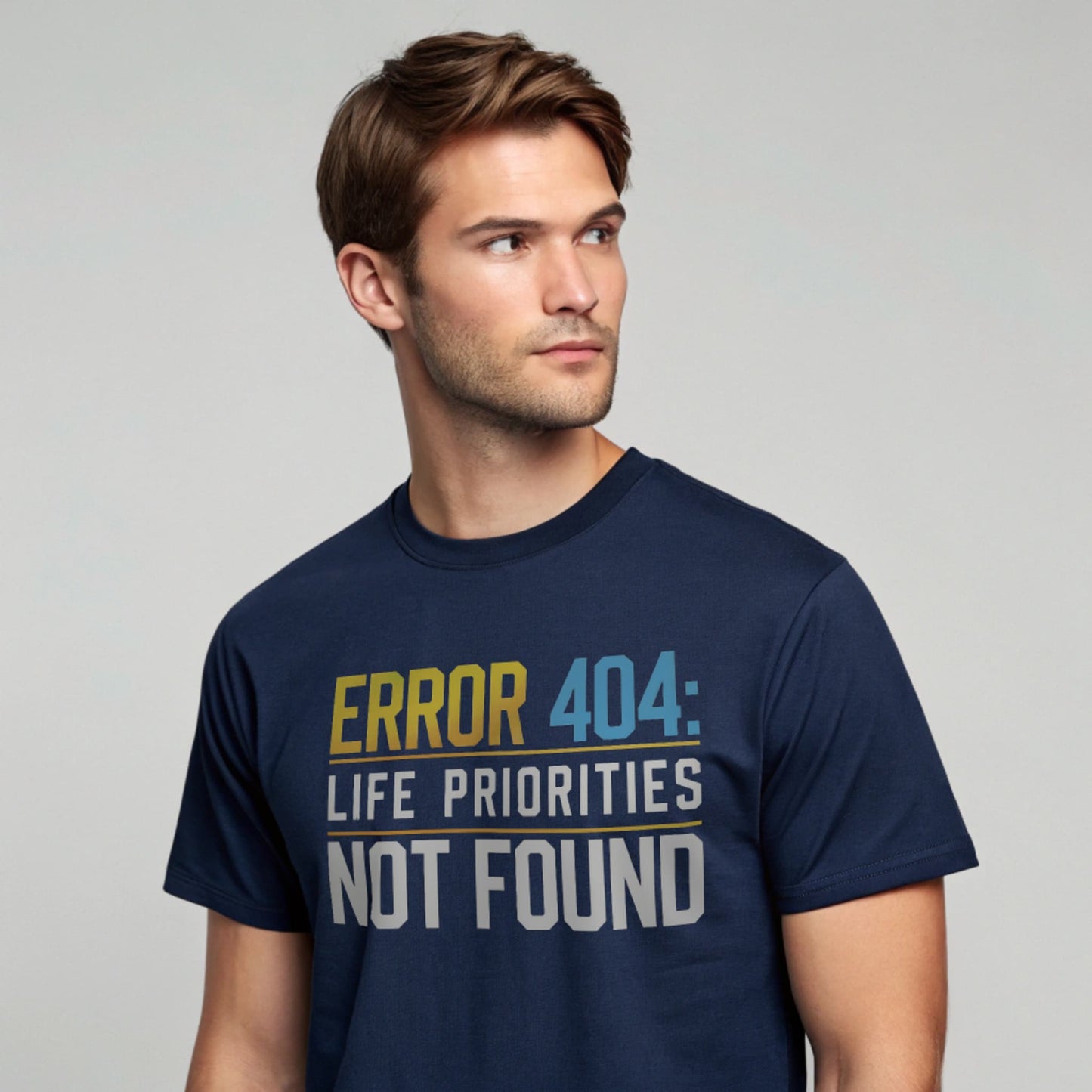 Male model wearing a navy crew-neck t-shirt with “Priorities Not Found” tech graphic, studio shot on a smooth pale-gray background.