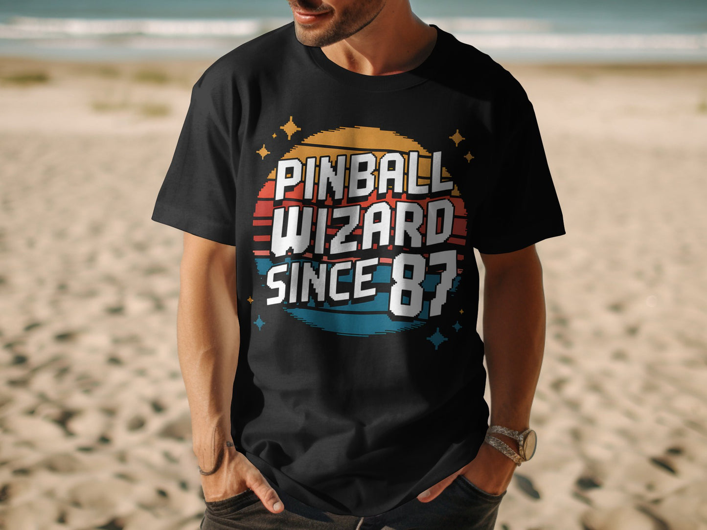 Man wearing Pinball Wizard 87 shirt outdoors on beach