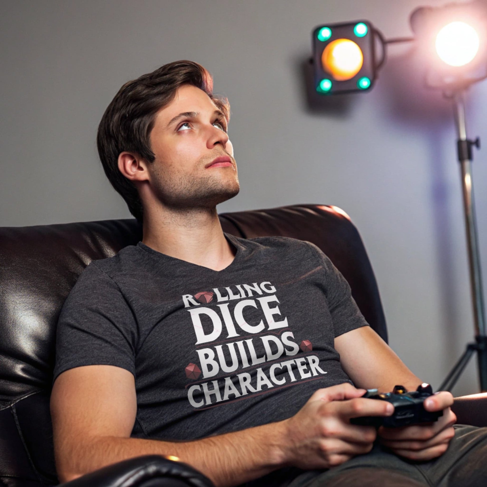 Dark Heather lifestyle mockup of Rolling Dice Builds Character tee in a gaming den with RGB lights and leather chair, male model gaming