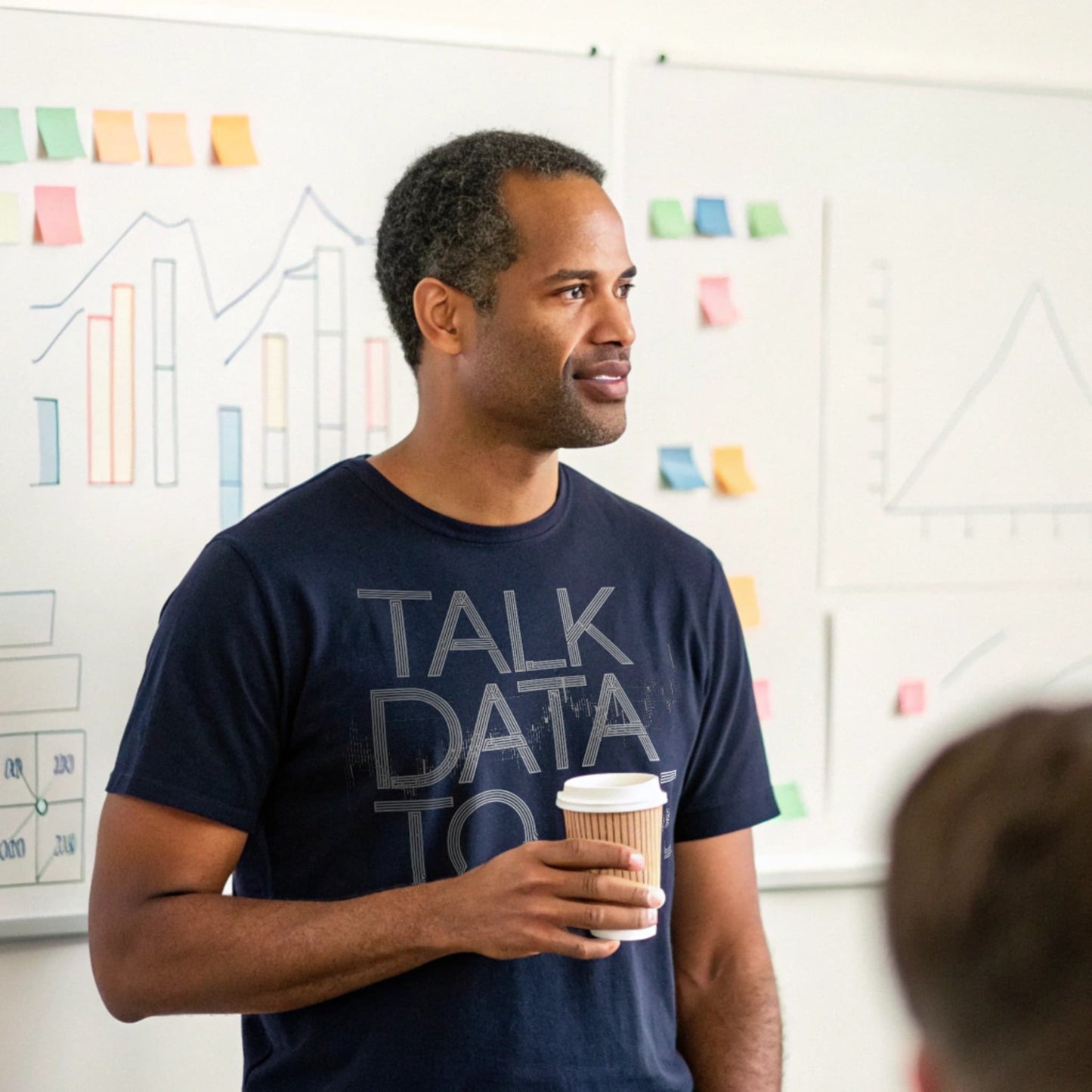 Man holding coffee giving presentation in navy “Talk Data to Me” T-shirt