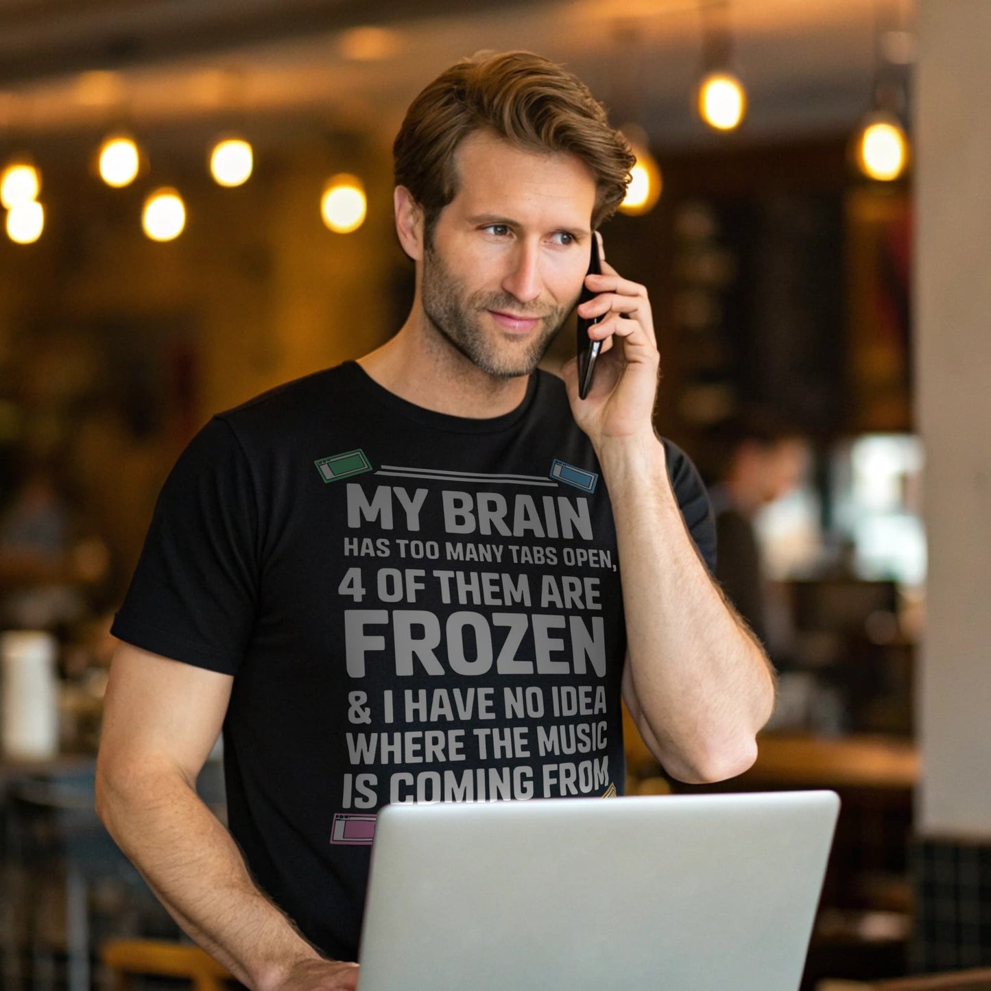 Hyper-realistic mockup of a 25–40-year-old man wearing a black Too Many Tabs T-Shirt holding a phone and coffee cup in a cozy café.