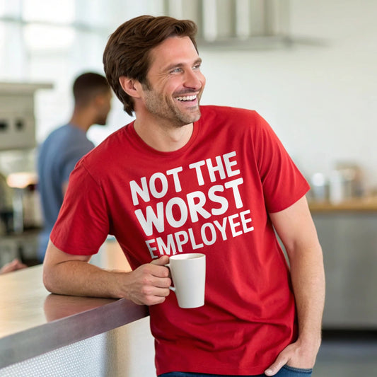 Hyper-realistic mockup of a 25–40-year-old man wearing a plain Gildan 64000 crew-neck red t-shirt (no graphics) leaning in a café holding a coffee mug.