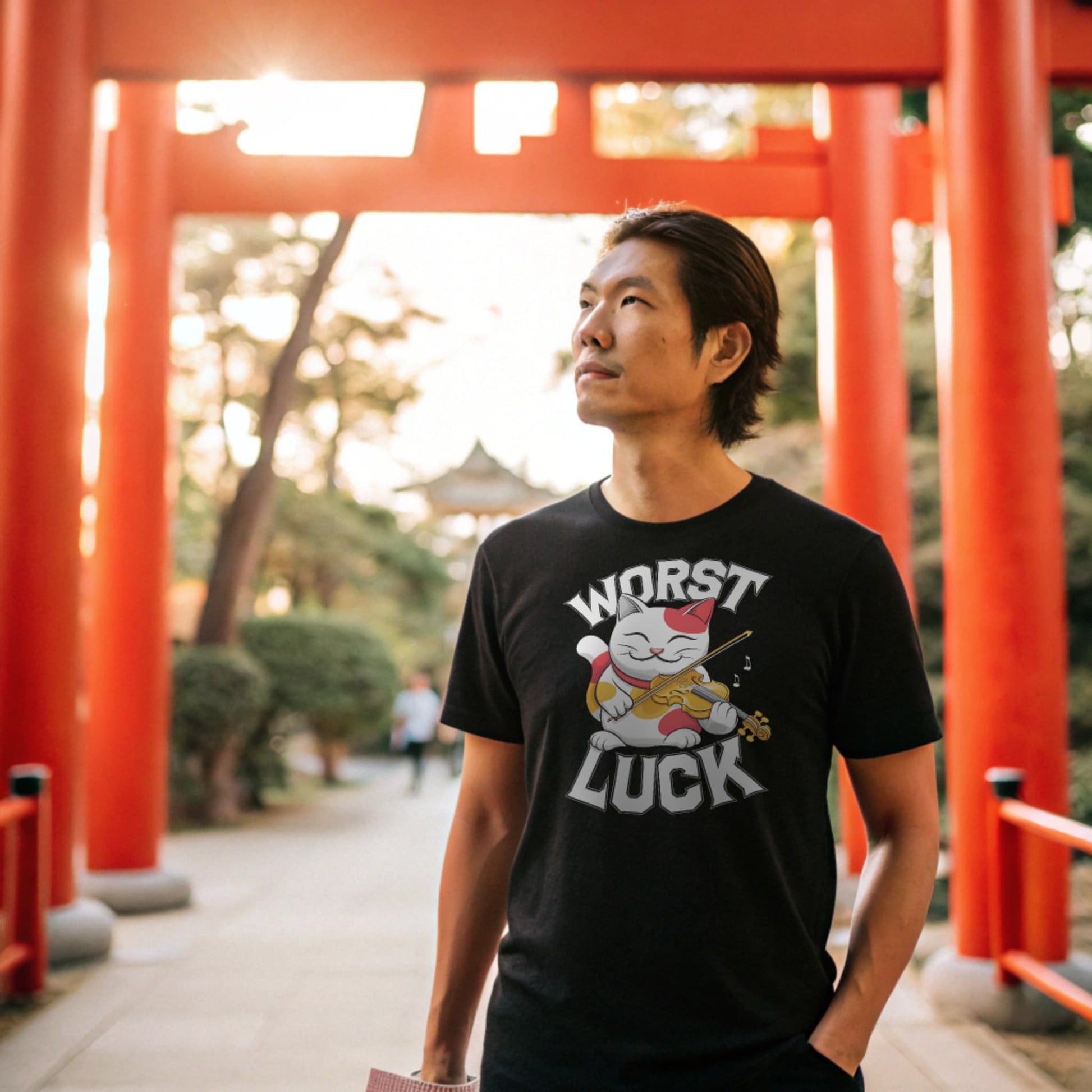 Black lifestyle mockup of Worst Luck T-Shirt on a male model under a red torii gate at a Shinto shrine, plain crew neck