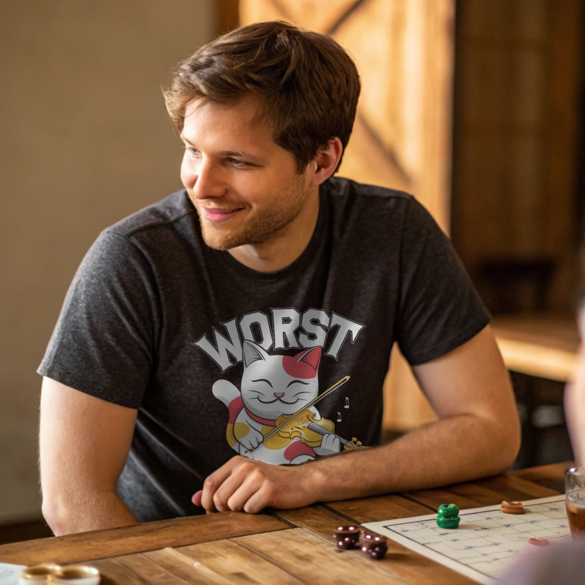 Dark Heather lifestyle mockup of Worst Luck T-Shirt on a male model seated at a wooden gaming table with dice and miniatures