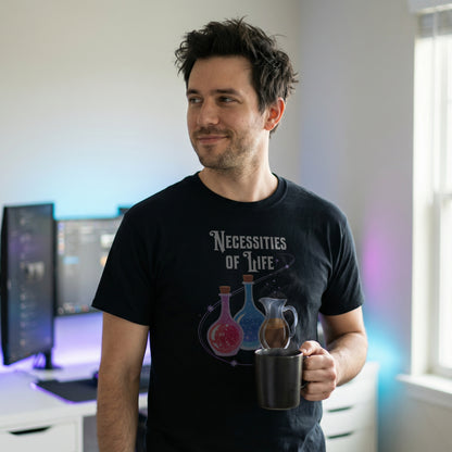 Man wearing a black Necessities of Life T-shirt holding a coffee mug in a workstation setup