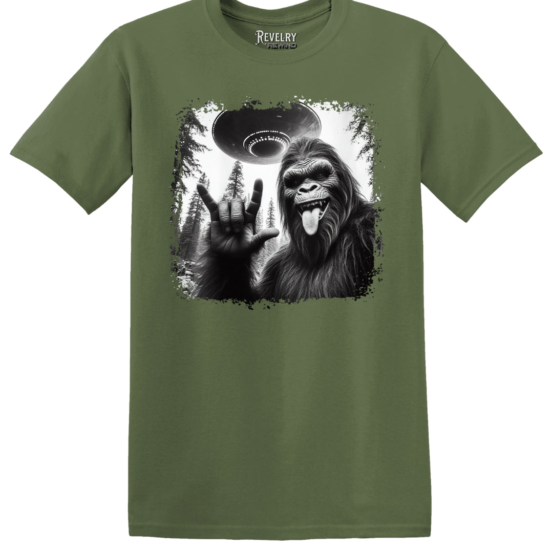 Flat lay of Bigfoot UFO Rocker design on military green t-shirt