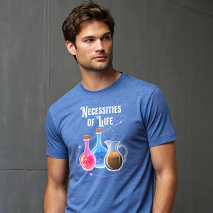 Male model leaning by a window in a heather royal crew-neck t-shirt with “Necessities of Life” potion graphic, lifestyle shot.