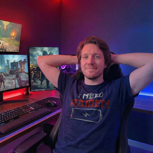 Man wearing navy I Need Ramen T-Shirt relaxing in a gaming setup