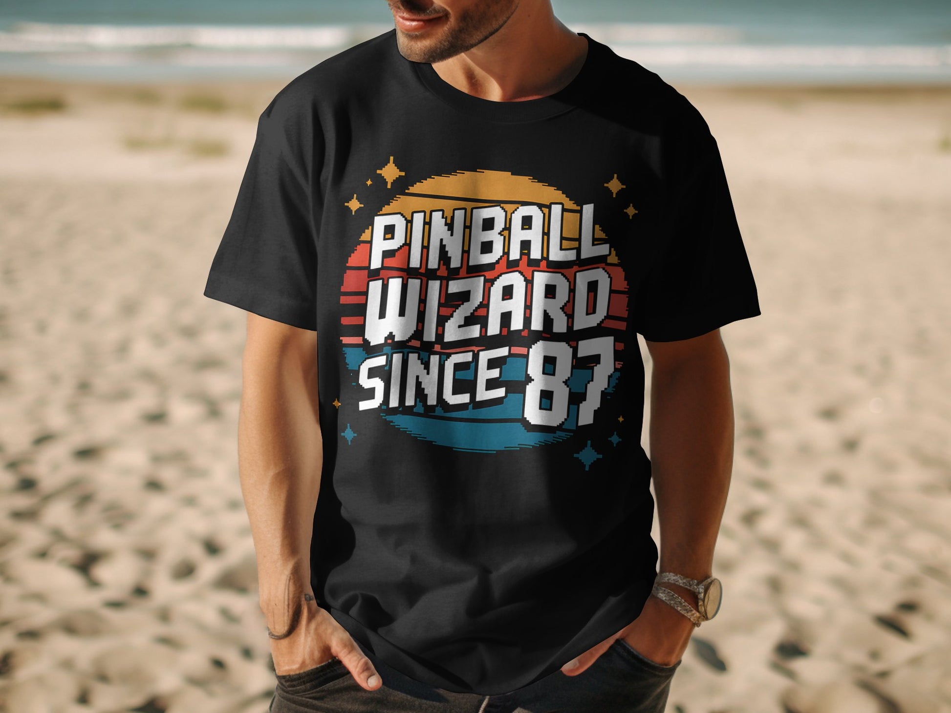 Man wearing Pinball Wizard 87 shirt outdoors on beach