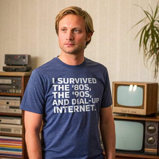 Realistic mockup of a man in Heather Indigo t-shirt that reads “I Survived the ‘80s, the ‘90s, and Dial-Up Internet” standing in a retro living room