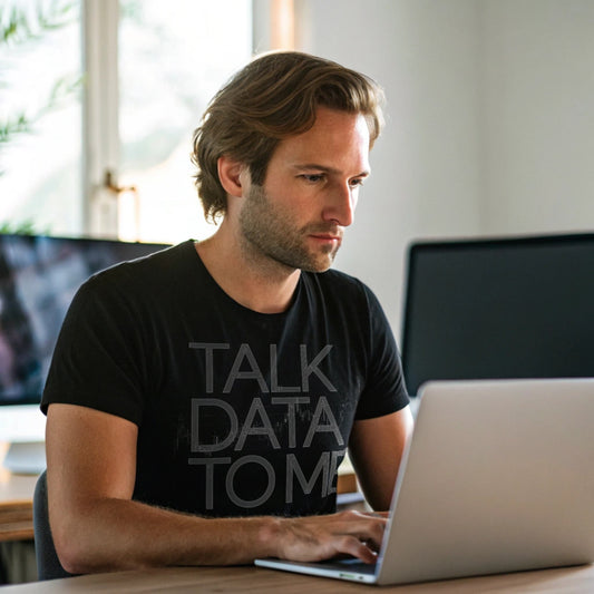 Man working at laptop wearing black “Talk Data to Me” T-shirt indoors