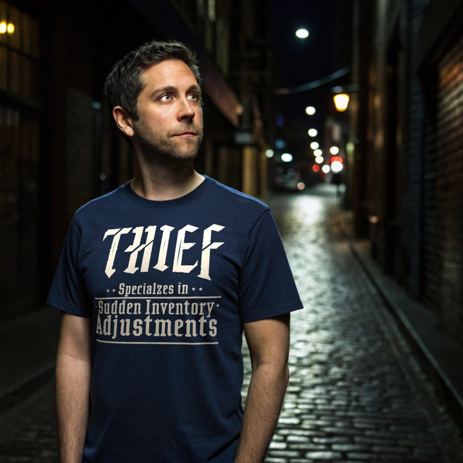 Man wearing Navy Thief RPG T-Shirt standing in a moody cobblestone alley at night