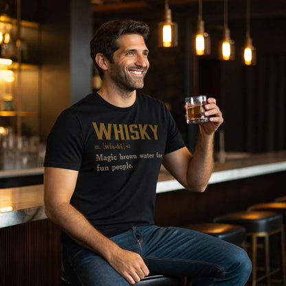 Lifestyle mockup of smiling man at a bar wearing the Black Whisky Definition T-Shirt and holding a whisky glass.