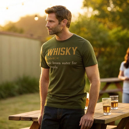 Lifestyle mockup of man in a backyard at golden hour wearing the Military Green Whisky Definition T-Shirt.