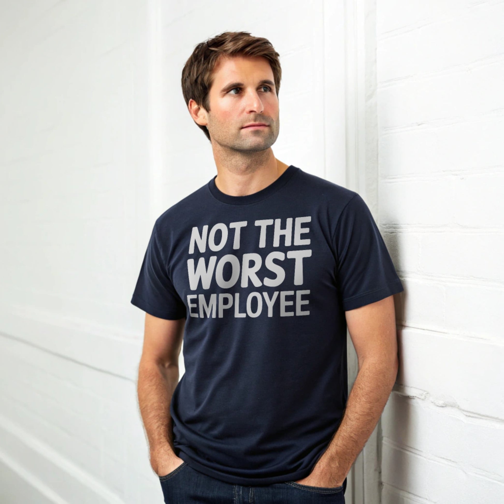 Hyper-realistic mockup of a 25–40-year-old man wearing a plain Gildan 64000 crew-neck navy t-shirt (no graphics) standing face-on against a white brick wall.