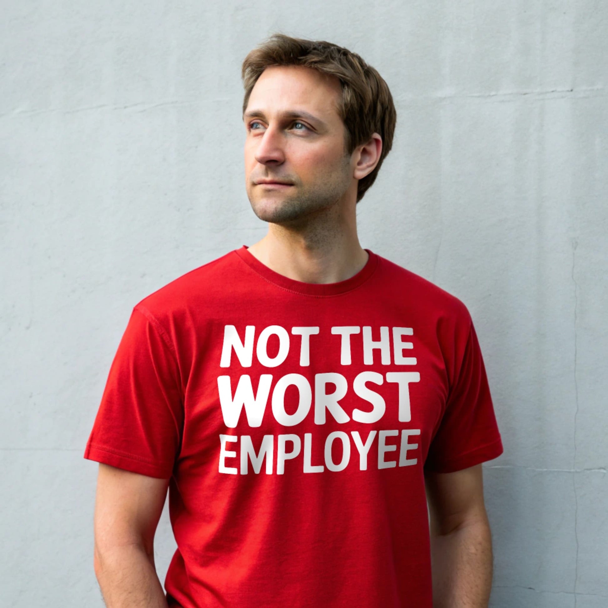 Hyper-realistic mockup of a 25–40-year-old man wearing a plain Gildan 64000 crew-neck red t-shirt (no graphics) standing face-on against a light gray wall.